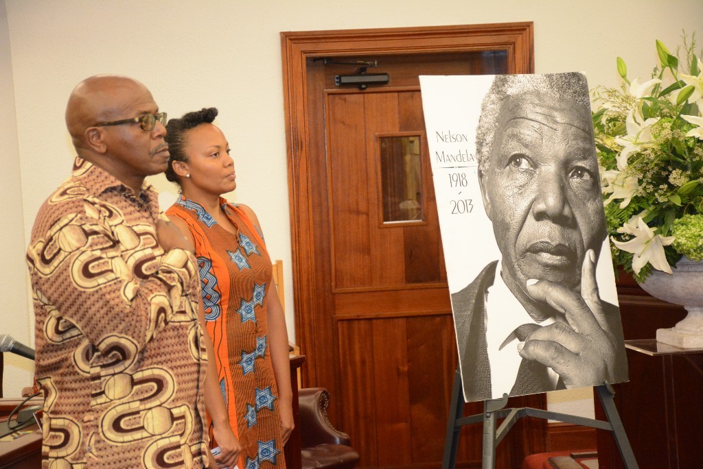 Legislature chambers next to a poster of Nelson Mandela Sen. Positive Nelson blows a call on the conch, while Sen. Tregenza Roach watches the Pan African flag being raised. (Photo by Barry Leerdam, provided by the Legislature of the Virgin Islands)