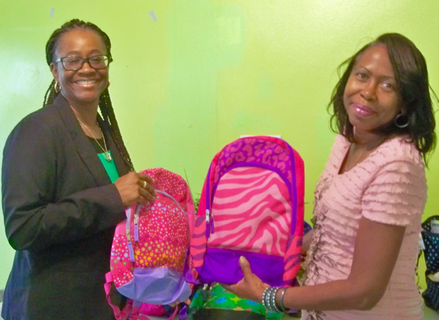 CCA President Jamilah Henry gives backpacks to Delores Coleman, assistant director at Queen Louise.