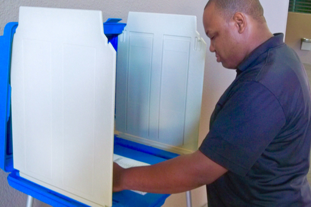 Terrell Alexandre demonstrates how the ballots and voting machines work.