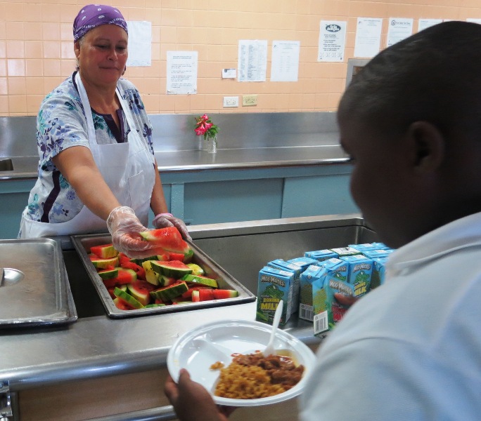 Claude O. Markoe School food service worker Sonia Nieves adds a slice of homegrown watermelon to a student meal.