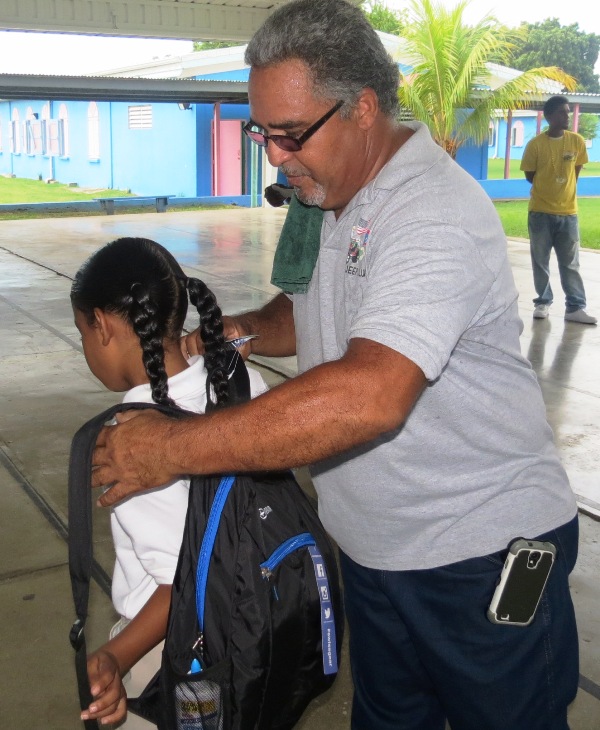 Victor Huertas Sr. helps student put on new backpack.