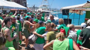 Crowds of people in shirts saying 'Feeling Lucky' dance to Kurt Schindler's music on the boardwalk.