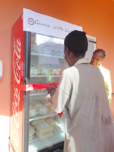 A client cuts the ribbon Wednesday and receives the first meal from the Giving with Grace refrigerator serving the homeless population of Frederiksted. Masserae Webster, Frederiksted Health Care chief executive officer, applauds.
