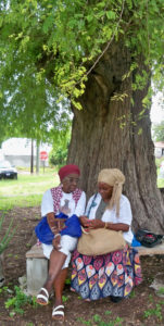 Asta Williams, left and Donna "Queen Asheba" Samuel trade tales under the tamarind tree.