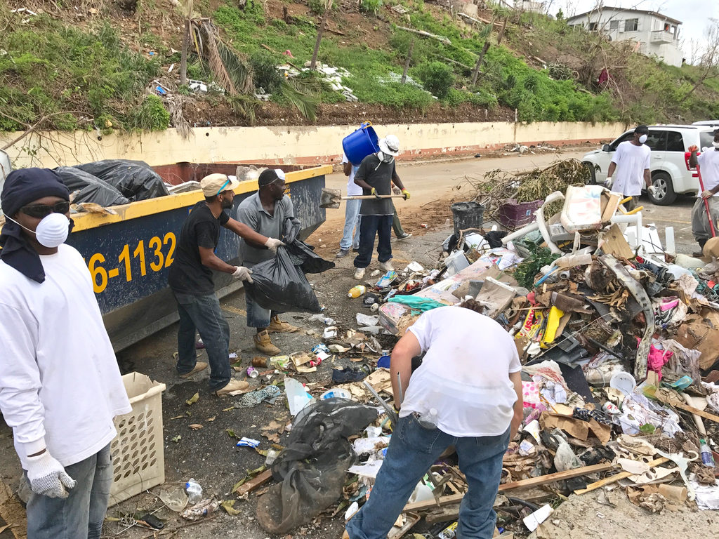 Residents work together Thursday to clean up trash piles in the hurricane-battered Tutu Hi-Rise Housing Community.