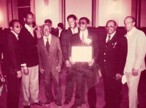 McIntosh receives an award from the National Endowment of the Arts with band members Meg Gordon, Isidore Griles, Frank Charles, Lloyd Thomas, Sylvester “Blinky” McIntosh, Anselmo Clarke and Gustave Petersen.