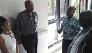 Health and hospital officials talk in a dimly lit corridor of the Myrah Keating Smith Clinic about the future of health care on St. John, with Gov. Kenneth Mapp, right. Also pictured, from left, Dr. Tai Hunte, Dr. Bernard Wheatley, and Darryl Smalls.