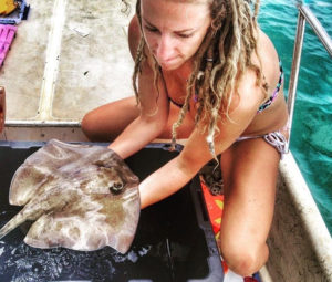 Graduate Michele Donihe has caught – and will release – a juvenile Southern stingray, which is the focus of her research.