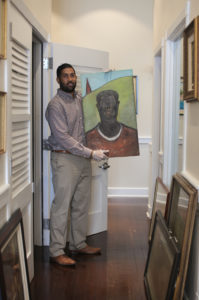 Julio Encarnacion holding painting 'Strength and Power,' artist unknown, during assessment and inventory of St. Thomas Government House Annex. (Photo submitted by Julio Encarnacion)