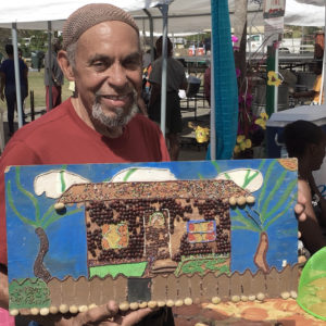 Eddie Bruce displays a 'bead/seed art' collage made by Luciah Polius when she was 11 years old.