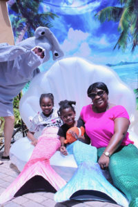 Festival attendees Semaya Smith, Mia Tucker and Cherise Tucker pose as mermaids using a booth created by entertainer, Mermaid Kelly, which taught guests about the harmful of affect plastics on aquatic creatures. Kristen Grimes, research assistant professor of watershed ecology at the University of the Virgin Islands, dressed as a shark and jumped in with the three mermaids in celebration of the event.