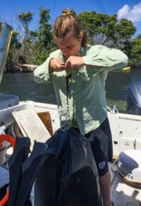 Volunteer Owen Clower weighs a bag of plastic trash on the garbage boat. (April Knight photo)