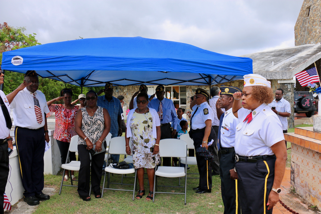 Veterans salute as Taps is played for all those who are remembered on Memorial Day. In the center is Ana Hernandez McIntosh, who placed the ceremonial wreath on the grave of her husband, Gleston McIntosh. (Linda Morland photo)