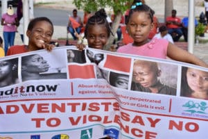 Three youngsters from hold a 'Adventists Say No to Violence' banner at the Eliza James-McBean clock tower in Frederiksted.