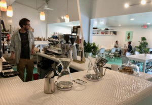 Behind the penny tile bar, barista Aiden Brewer prepares coffee for customers. (Photo by Zack Zook)