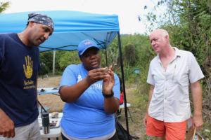 Alicia Odewale studies a new piece of tile that was found on the grounds as William White, left, and Jeffery Miller look on. (Source photo by Linda Morland)