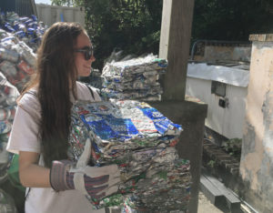 Volunteer Maven Parsil stacks crushed aluminum cans at Island Green Living Association. (Source photo by Amy Roberts)
