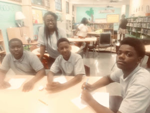 Eighth grade honor students Ameer Norman, Nyah Laudat and Tyreak Creighton with English teacher Chenelle John-Heard. (Source photo by Elisa McKay)