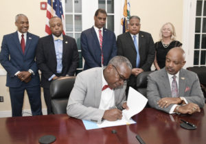 Gov. Albert Bryan, Jr. signs into law new amendments to the territory’s Hotel Development Act during a ceremony Monday. Joining him were: Lt. Gov. Tregenza Roach, Finance Commissioner Kirk Callwood Sr., Tourism Commissioner Joseph Boschulte, Chief Executive Officer of the Economic Development Authority Kamal Latham, Senator Kurt Vialet and President of the Hotel and Tourism Association, Lisa Hamilton. (Photo submitted by Government House)