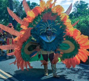 A feathered parade troupe member seems to create an odd creature as it marches through Frederiksted. (Source photo by Don BUchanan)