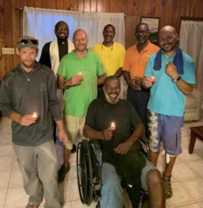 The Rev. Anthony Abraham blesses the Our Lady of Charity House in March. Standing, from left, are resident Jerry Newton, the Rev. Anthony Abraham, resident Josh Libby, deacons Cassius Mathurin and Evans Doway and resident Kevin Benton Jr. gather around Ervince 'Hollywood' Phillip.