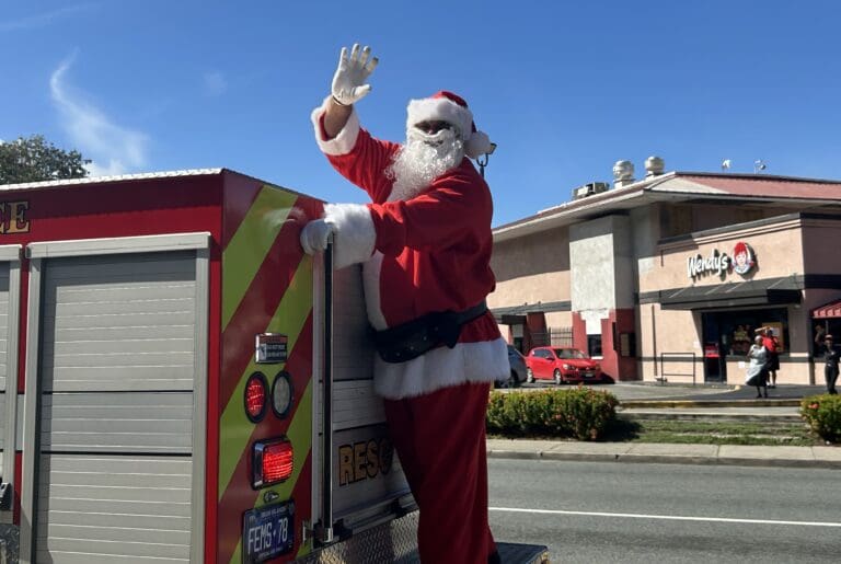 Santa waves to the crowd from his island-style chariot – a V.I. Fire and Emergency Medical Services truck. (Source photo by Siân Cobb)